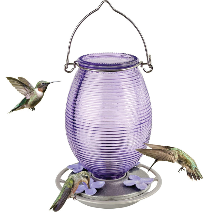 Purple glass hummingbird feeder with three hummingbirds around it on a white background