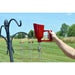 Person using a red funnel to fill bird feeders on a grassy outdoor setting