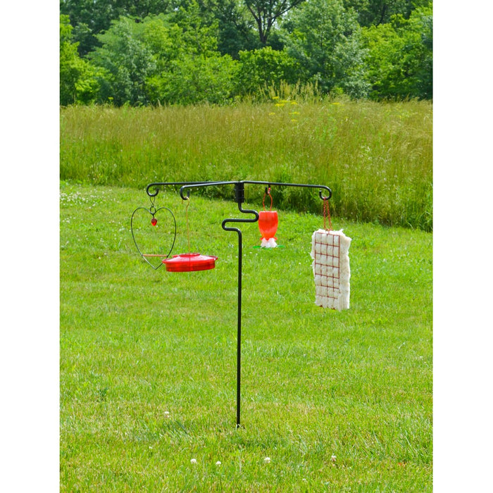 Bird feeder stand with multiple bird feeders on a grassy field