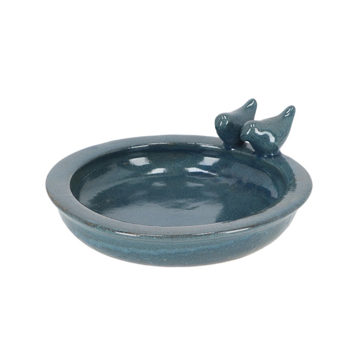 Blue ceramic bird bath with two birds on a white background