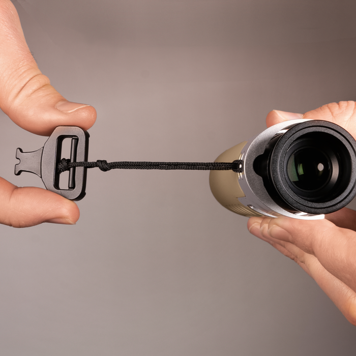 Two hands holding a camera lens and a lens cap against a gray background