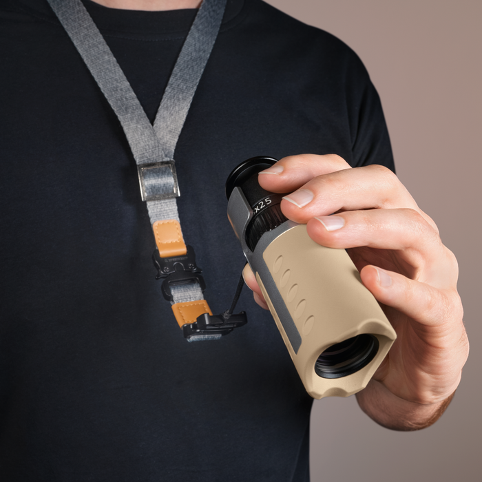 Person holding a rangefinder with a lanyard on a neutral background