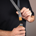 Person holding a gray strap with a buckle against a black background