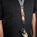 Person wearing a black shirt with a camera strap and lens attached, on a dark background