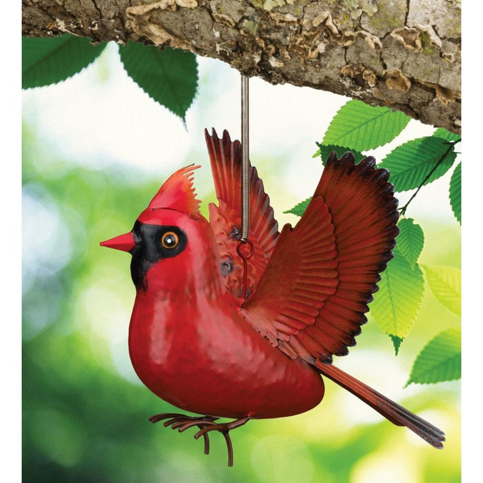 Red cardinal bird ornament hanging from a branch with a green leafy background