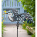 Decorative heron garden stake with a blurred garden background