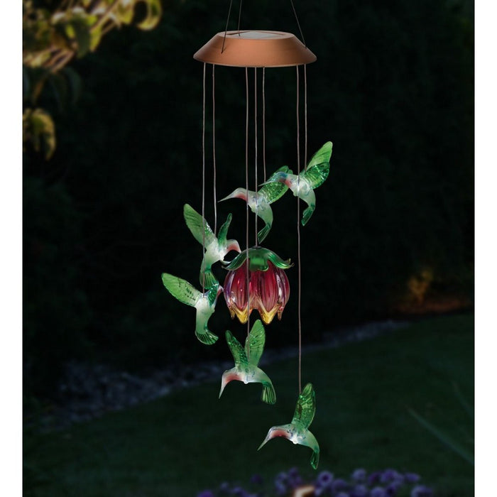 Solar-powered hummingbird and flower mobile with glowing effect on a dark background
