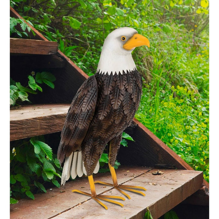 Decorative eagle sculpture on a wooden platform with greenery in the background