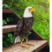 Decorative eagle sculpture on a wooden platform with greenery in the background