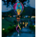 Colorful wind chime with dragonfly design against a blurred outdoor background
