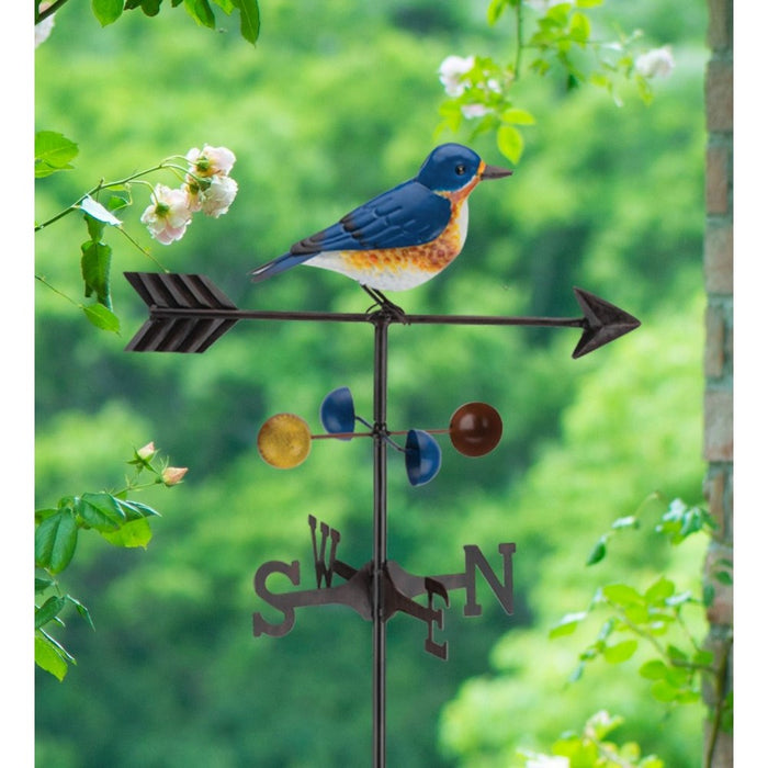 Decorative weathervane with a bird design against a green foliage background