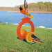 Bird feeder with oranges and birds perched on it by a lake