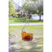 Glass bird feeder with orange berries hanging in a garden setting