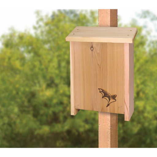 Wooden bat house on a post with a blurred green background
