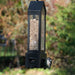 Bird feeder with a bird perched on it against a blurred natural background