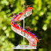 Colorful spiral hummingbird feeder with hummingbirds around it against a green blurred background