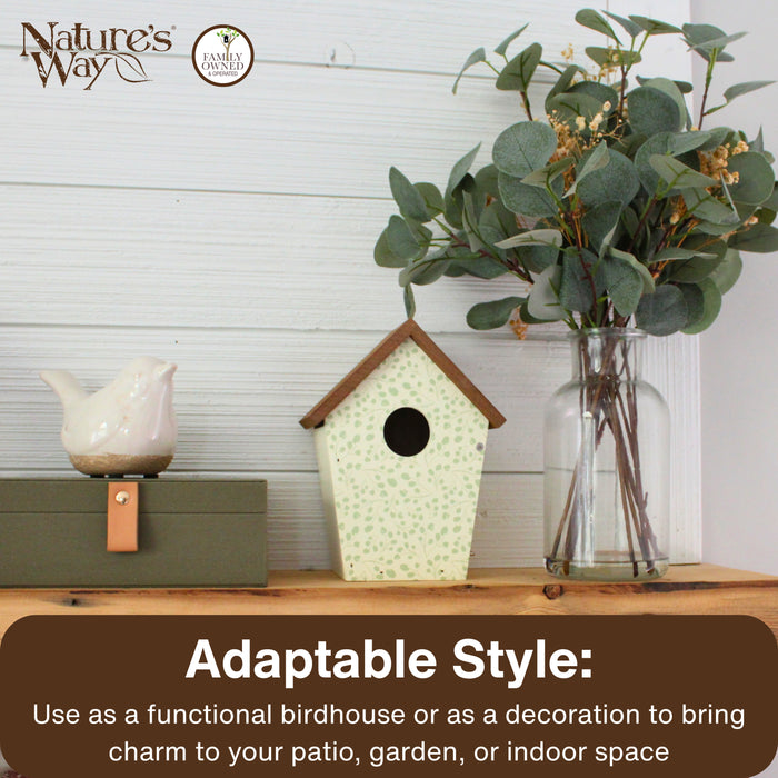 Decorative birdhouse and vase with greenery on a wooden surface, featuring Nature's Way branding.