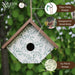Birdhouse with green leaf pattern and 'Nature's Way' branding, set against a blurred green background.
