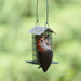 Woodpecker perched on a bird feeder with a blurred green background