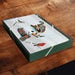A square decorative box with a dark green lid featuring a printed illustration of a horse and rider, placed on a dark wooden surface.